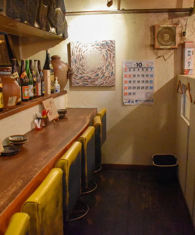 泡盛の瓶が並ぶ、温かい雰囲気のカウンター席